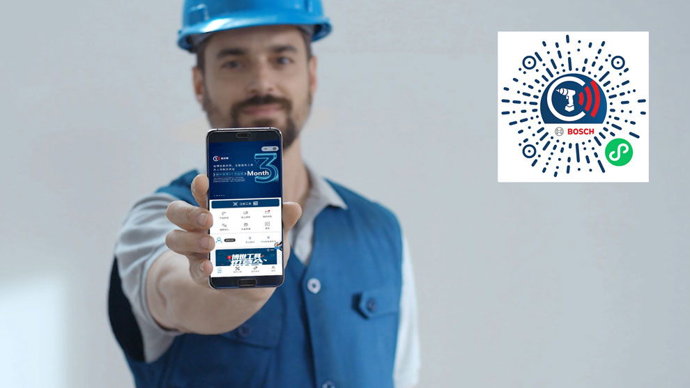一名穿着蓝色工作服的男子手持一部带有博世应用程序的智能手机。