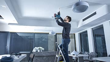 一名男子在办公室的梯子上使用博世专业工具。