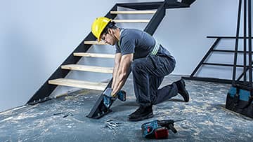 一名戴着头盔的工匠正在使用博世工具修理楼梯。