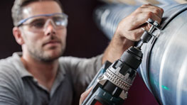 一名戴着护目镜的工匠正在使用一台黑色博世电钻。