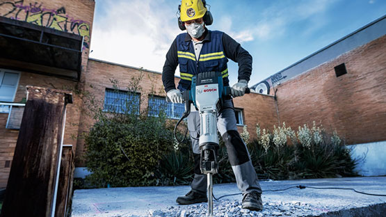 一名工人在户外使用博世锤处理混凝土。