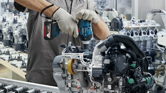 一名戴着头盔和口罩的工人正在使用博世专业工具。