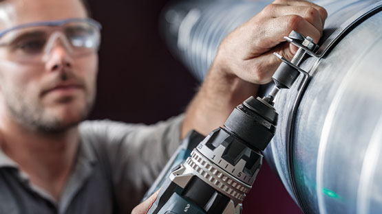 一名工匠在一根管道上使用博世专业电钻。