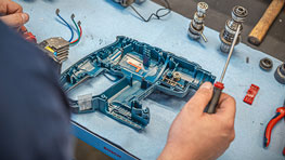 一个人在桌子上修理一把蓝色的博世工具。