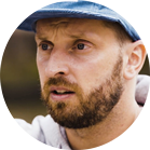 一个留着胡子的男人戴着蓝色的帽子，表情严肃。