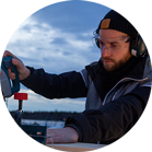 一个戴着耳机的男人在户外用博世锯切割木材。